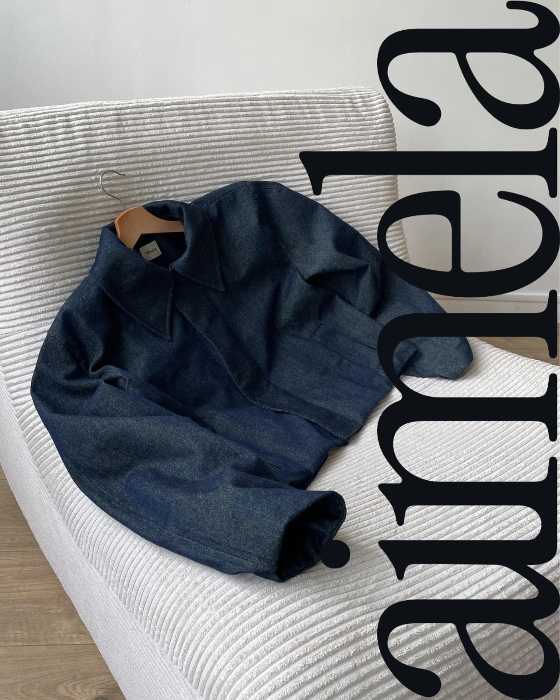 Vue de face de la veste La Gonflée en jean posé sur une chauffeuse avec le logo AimeLa